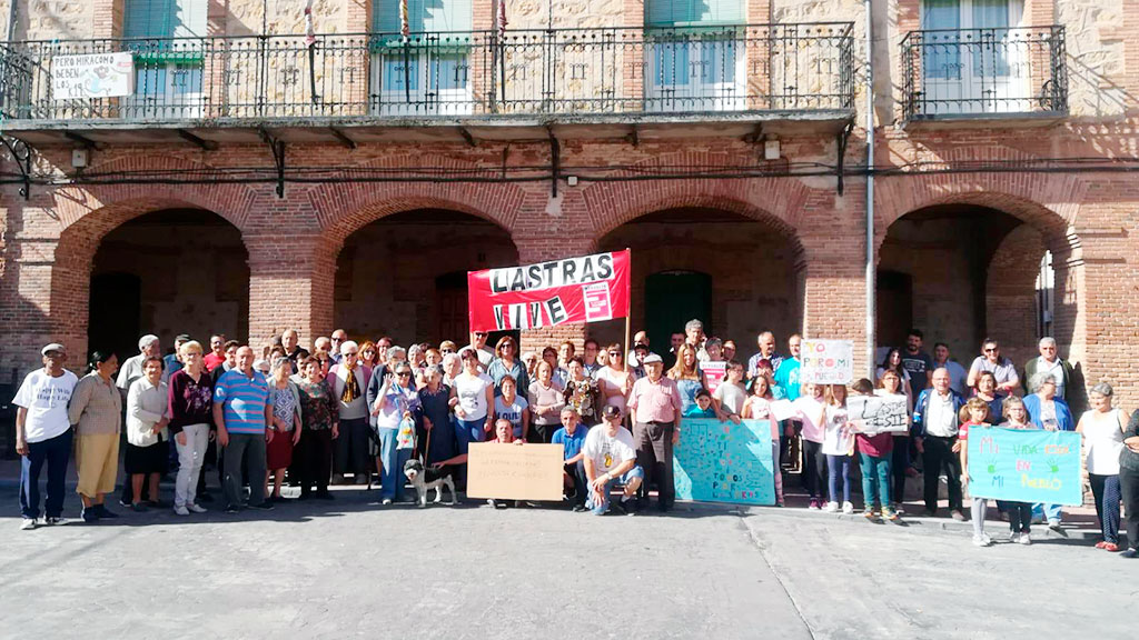 Los vecinos de Lastras de Cuéllar, mayores y pequeños, se cocentraron en la plaza del Ayuntamiento, bajo la pancarta 'Lastras Vive'. / el adelantado