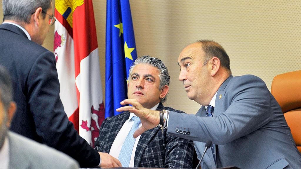 El presidente y el vicepresidente de la Diputación, conversan con un diputado de su grupo, en el pleno. / KAMARERO