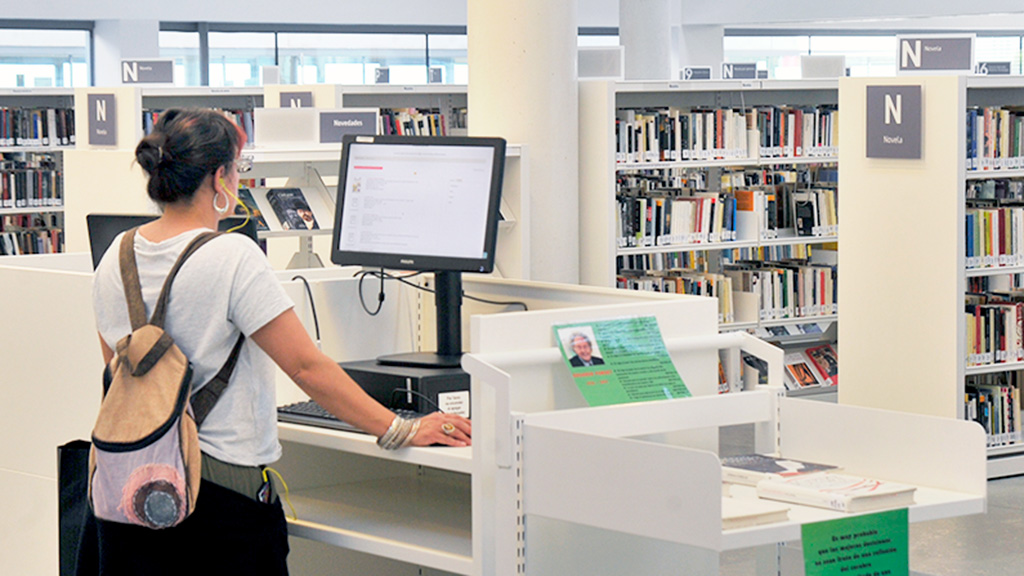 Una mujer consulta los fondos de la biblioteca. / Kamarero