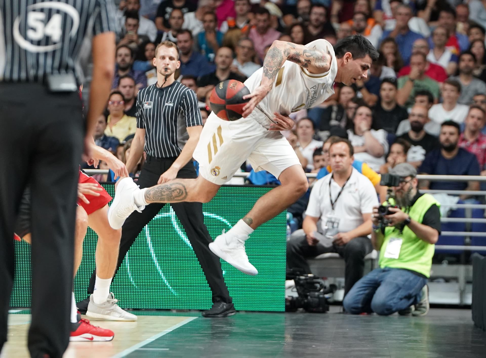 El alero argentino del Real Madrid, Gabriel Deck, intenta salvar un balón durante un partido. / EFE
