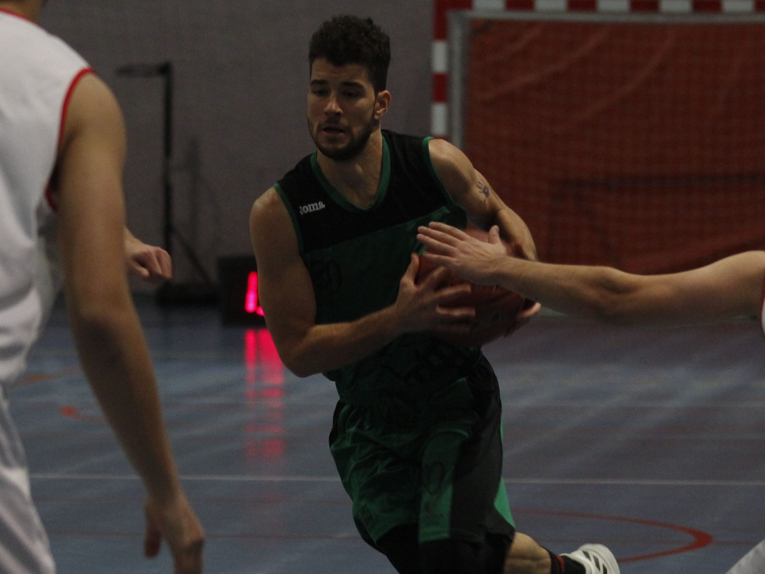 El jugador del CD Claret Joel Yagüe intenta irse de dos rivales del CB La Flecha, en el partido de cuartos. / NEREA LLORENTE