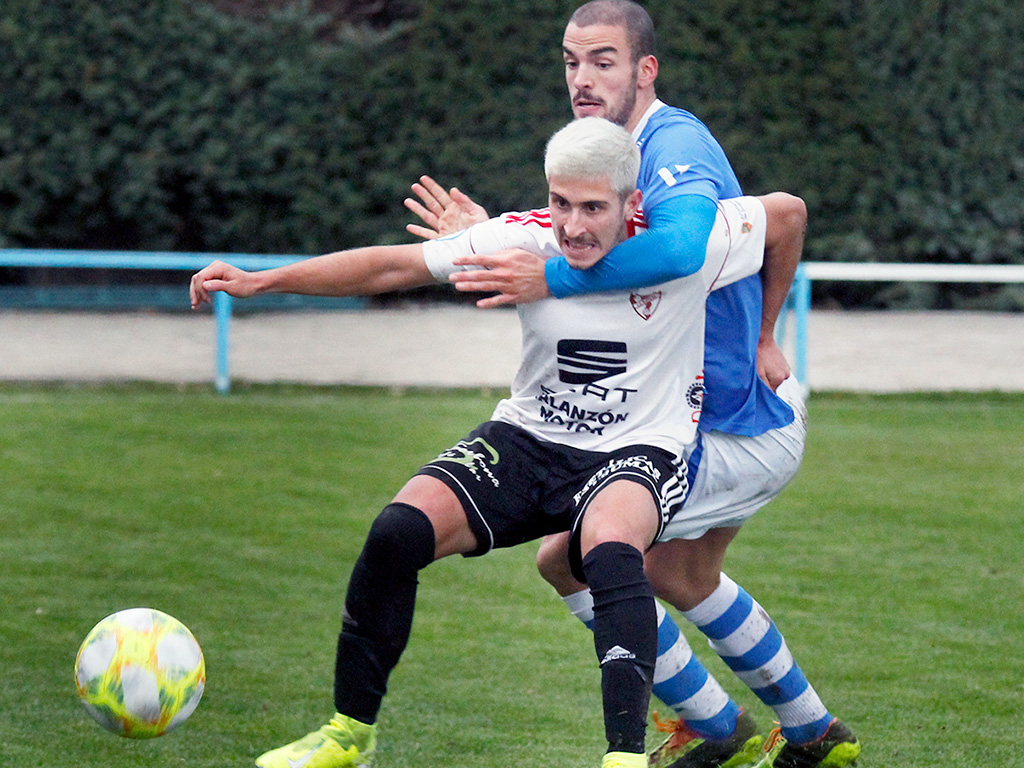 El centrocampista del CD La Granja Víctor Velasco impide que un rival del CD Bupolsa avance. / NEREA LLORENTE