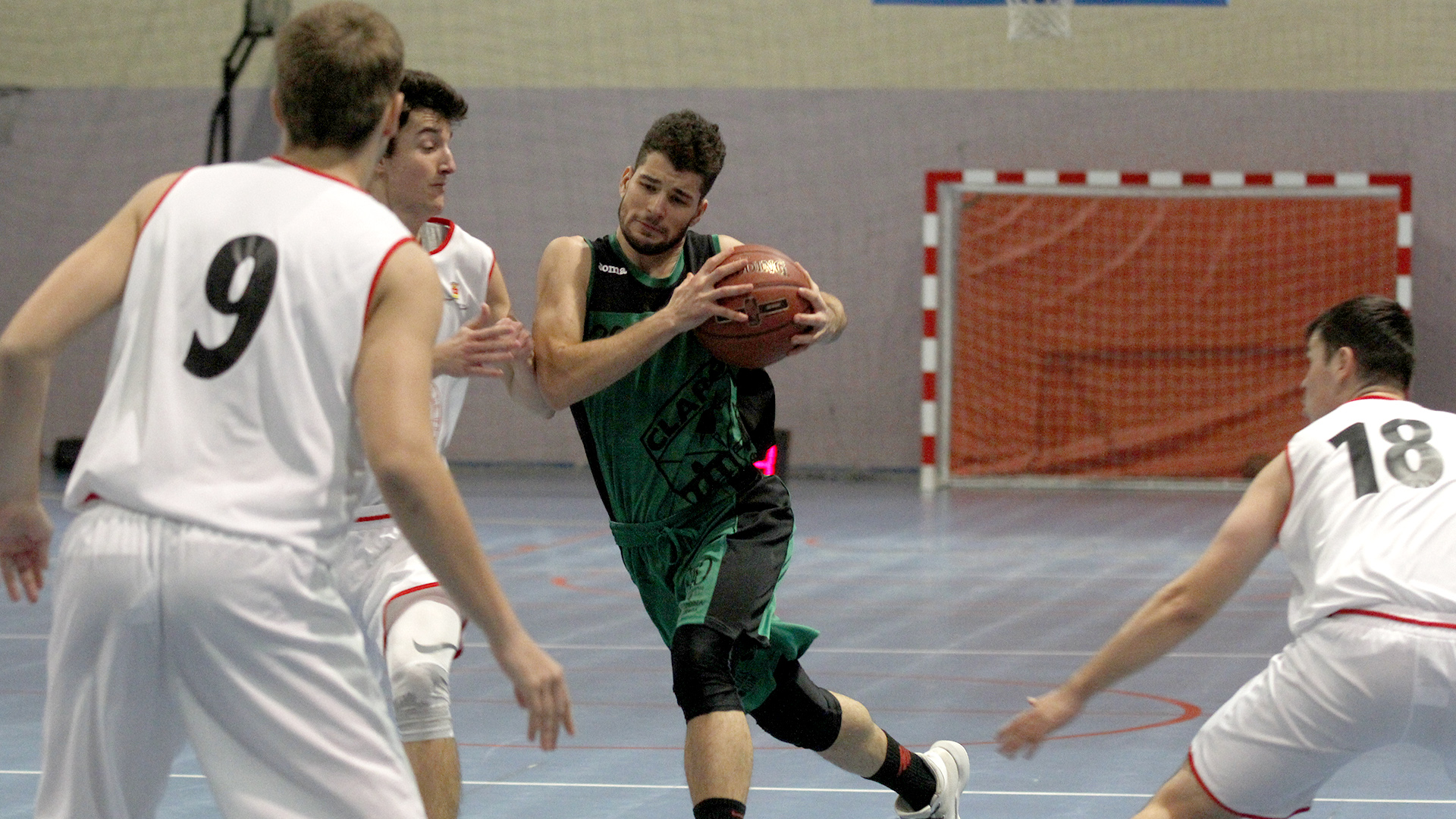 El jugador del CD Claret inicia la entrada hacia la canasta protegiendo el balón ante la mirada de su oponente. / NEREA LLORENTE