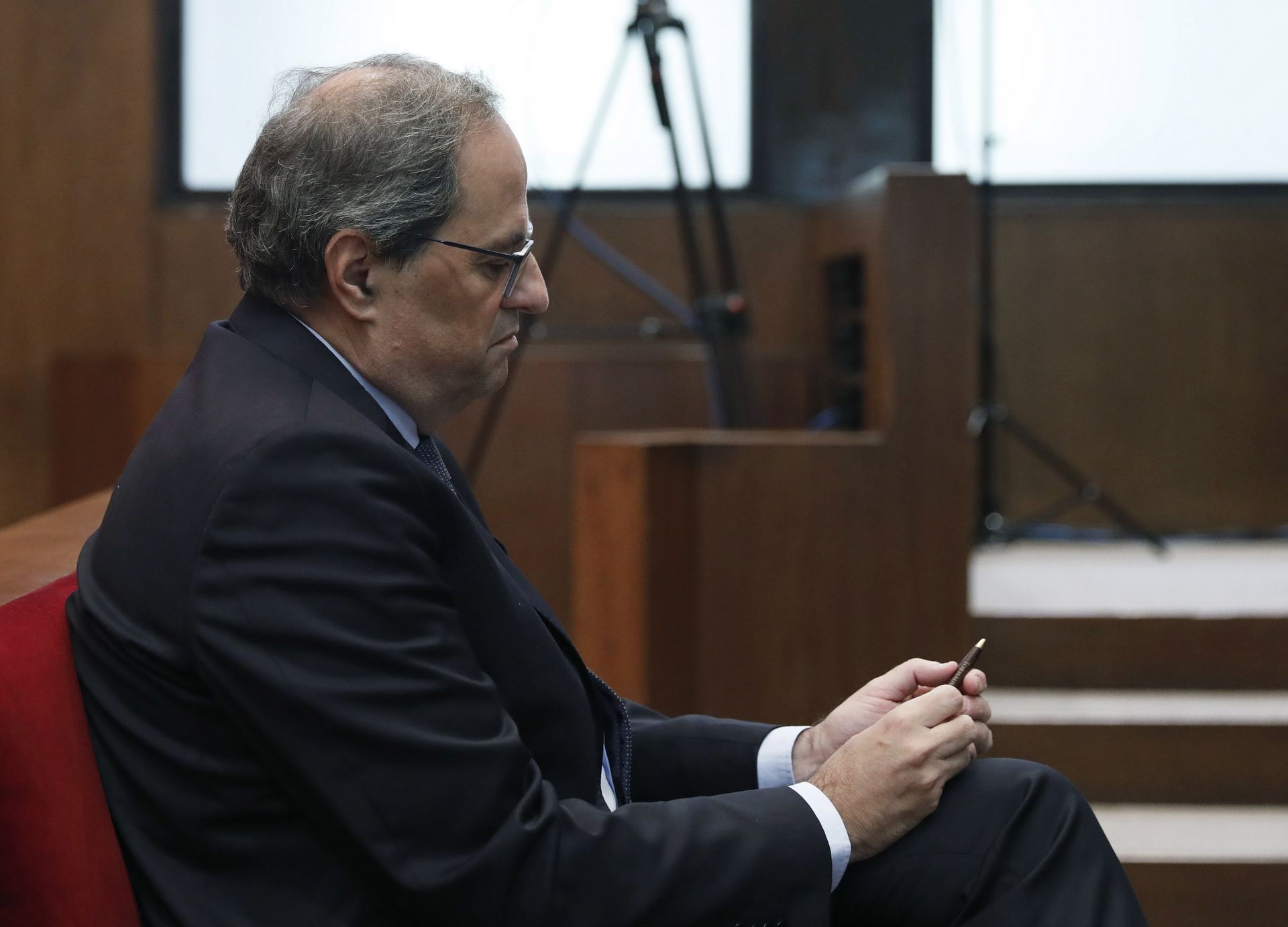 Quim Torra revisa su teléfono móvil durante la sesión del juicio. / EFE