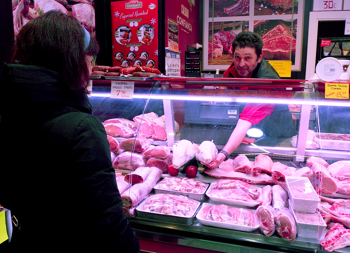 Un carnicero muestra dos cochinillos, uno de los productos más demandados en estas fechas. / NEREA LLORENTE