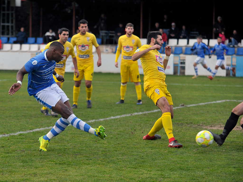 El delantero del CD La Granja Jonan Angulo marca el primero gol del partido tras un recoger un balón muerto en el área pequeña y batir al portero de La Bañeza CF Raúl Bayón. / KAMARERO