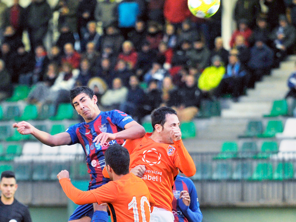 El defensa central de la Gimnástica Segoviana Javi Marcos remata con la cabeza una acción a balón parado por encima de los rivales. / KAMARERO