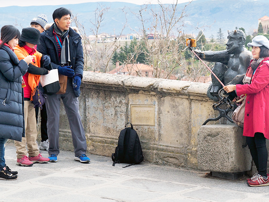 Varios turistas extranjeros se fotografían junto al diablillo.
