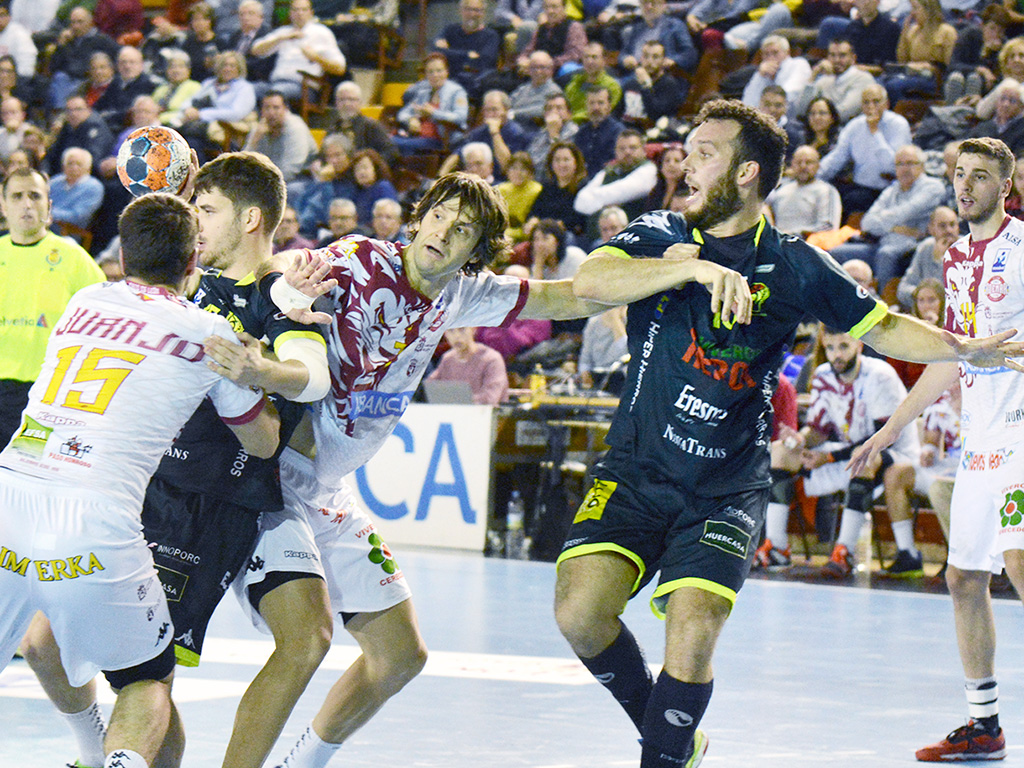 Rodrigo Pérez Arce busca compañero mientras es sujetado por la defensa del Ademar./ AMADOR MARUGÁN