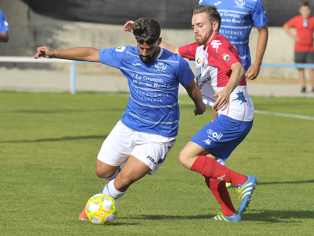 El jugador del CD La Granja Víctor Manuel Bravo ‘Vitolo’ se marcha de un rival del Atlético Tordesillas. / KAMARERO