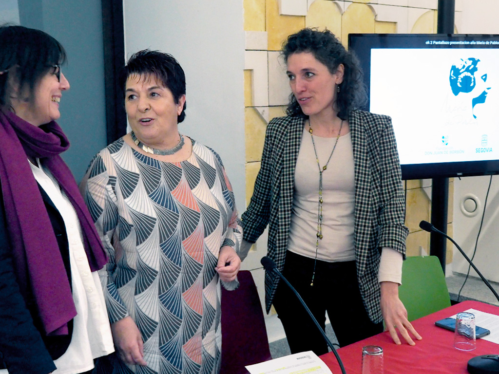 La concejala de Cultura, la alcaldesa y la coordinadora de la Fundación, junto al logo adaptado por el artista segoviano Christian Hugo para este aniversario. / Kamarero