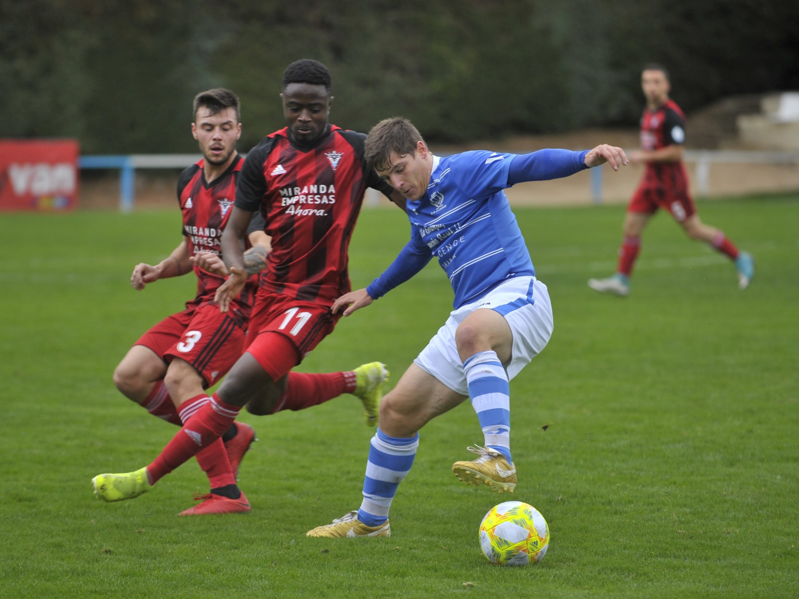 El delantero del CD La Granja Dani Lázaro controla un balón ante la presión de dos rivales. / KAMARERO
