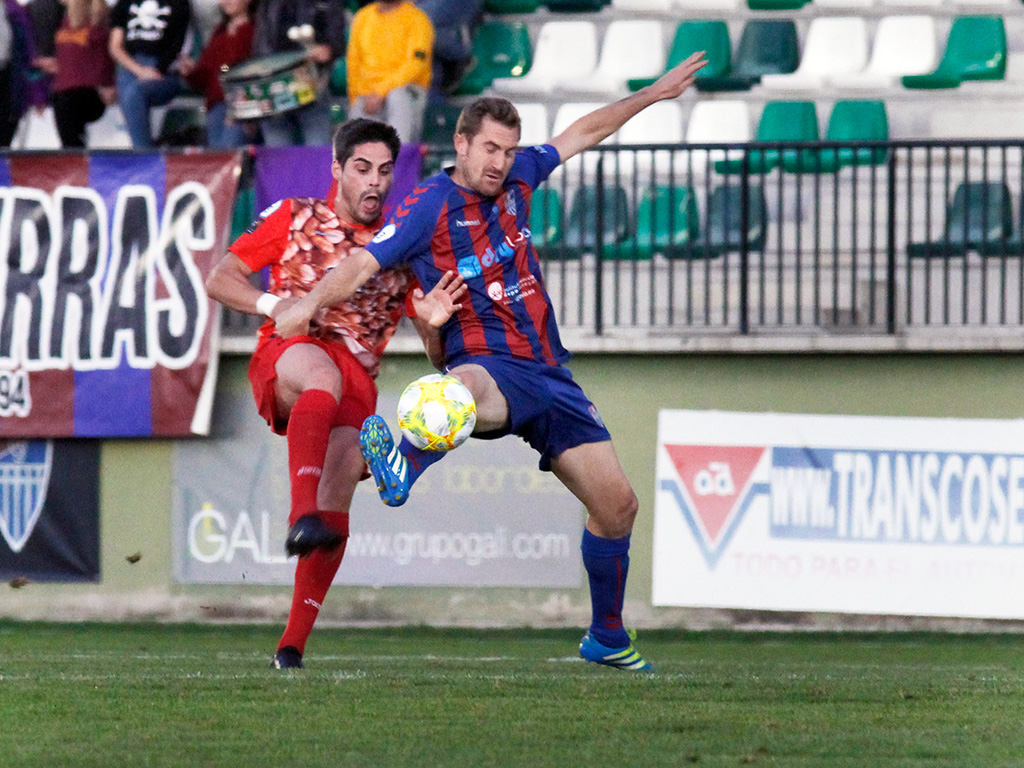 El juagdor del CD La Granja, Kike, y el de la Gimnástica Segoviana, Dani Arribas, pelean por un balón dividido durante el partido jugado en La Albuera. / NEREA LLORENTE