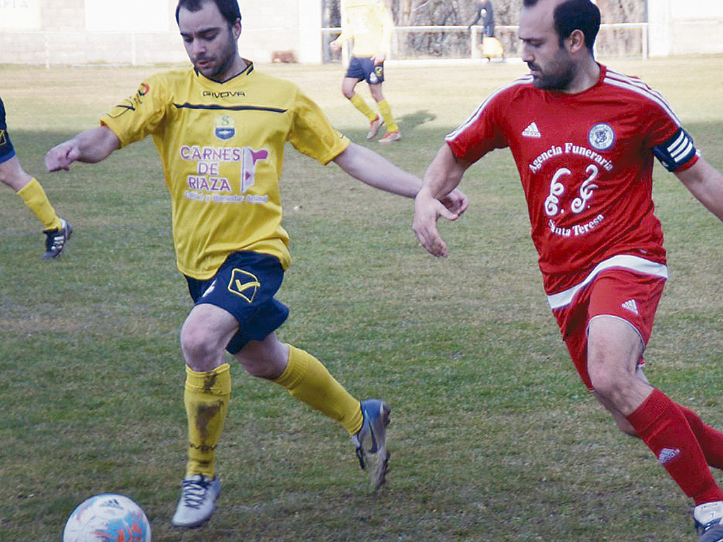 El delantero cuellarano Frutos trata de avanzar ante la oposición de Fran, del Sporting Riazano. / RUBÉN DE MIGUEL