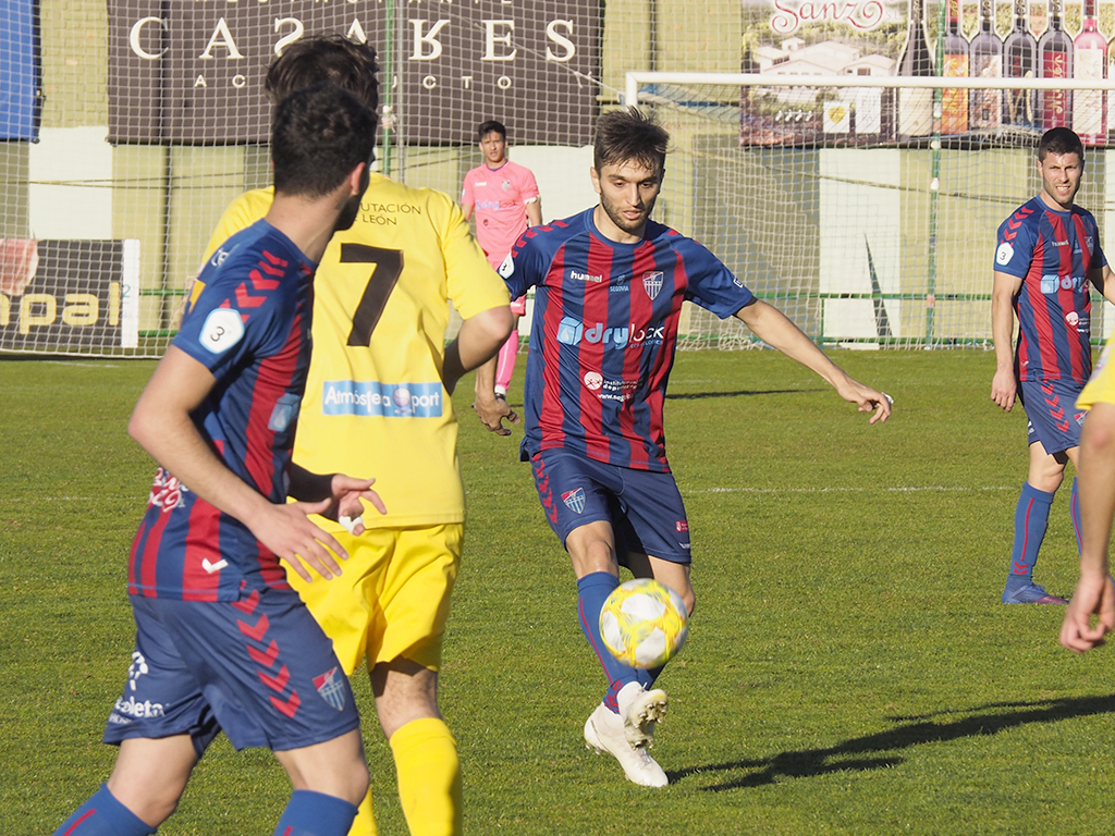 El atacante de la Gimnástica Segoviana Álex Conde mete un pase entre la defensa de La Bañeza. / KAMARERO
