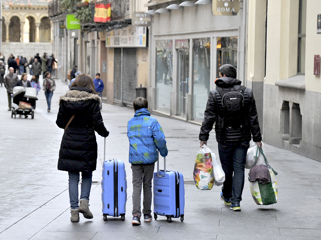 Una familia recorre la Calle Real de Segovia con bolsas y maletas. / Kamarero