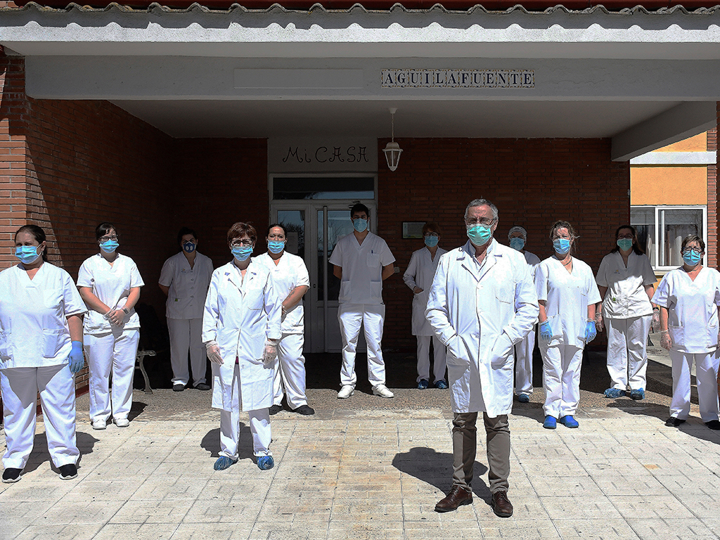 El director de la residencia para mayores de Aguilafuente en Segovia Agapito Fernández (c) junto con todos las trabajadoras del centro durante el confinamiento junto con los internos este domingo. EFE/Pablo Martin