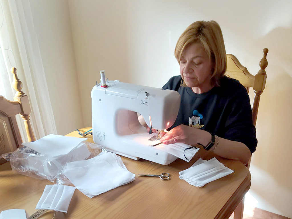 Una de las participantes trabaja, desde el salón de su casa, en la confección de un centenar de mascarillas. / E.A.