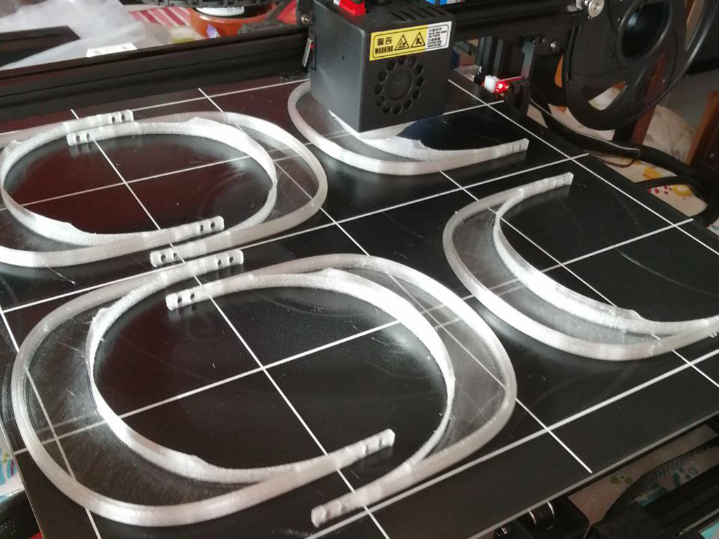 Una de las impresoras 3D que elabora viseras y, a la derecha, una pantalla de protección facial ya montada. / E. A.