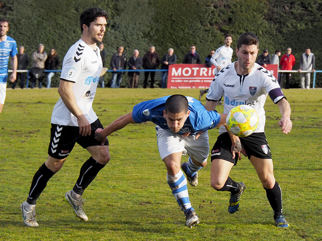 Los jugadores de la Segoviana Rubén Yubero y Manu intentan para a Tomás Casas, del CD La Granja. / KAMARERO