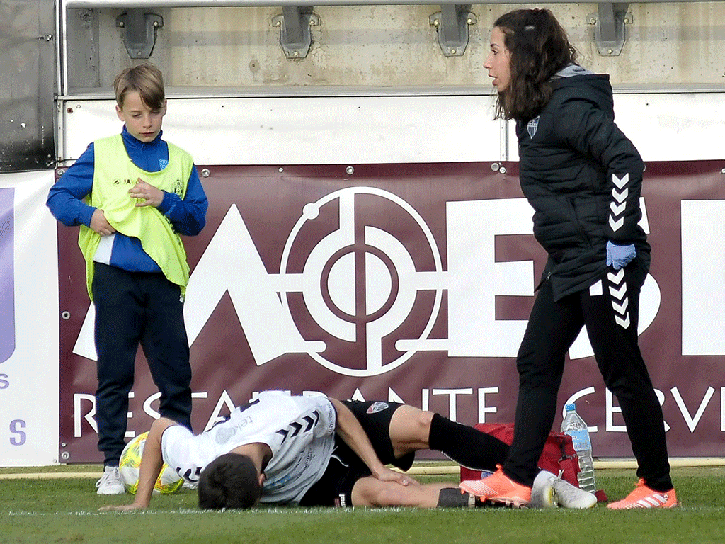 Álex Conde se duele de la rodilla mientras la fisioterapeuta del equipo espera a las asistencias./ JUAN MARTÍN-GIMNÁSTICA SEGOVIANA