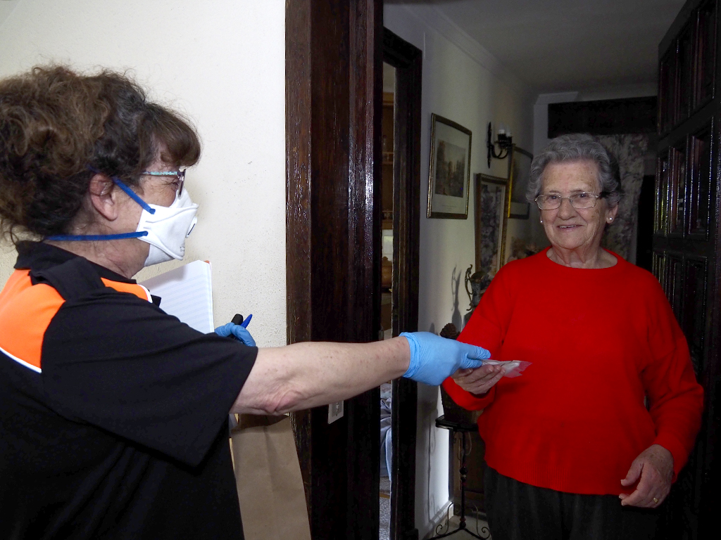 La voluntaria de Protección Civil, María Jesús Fernández, repartiendo mascarillas ayer a sus vecinos.