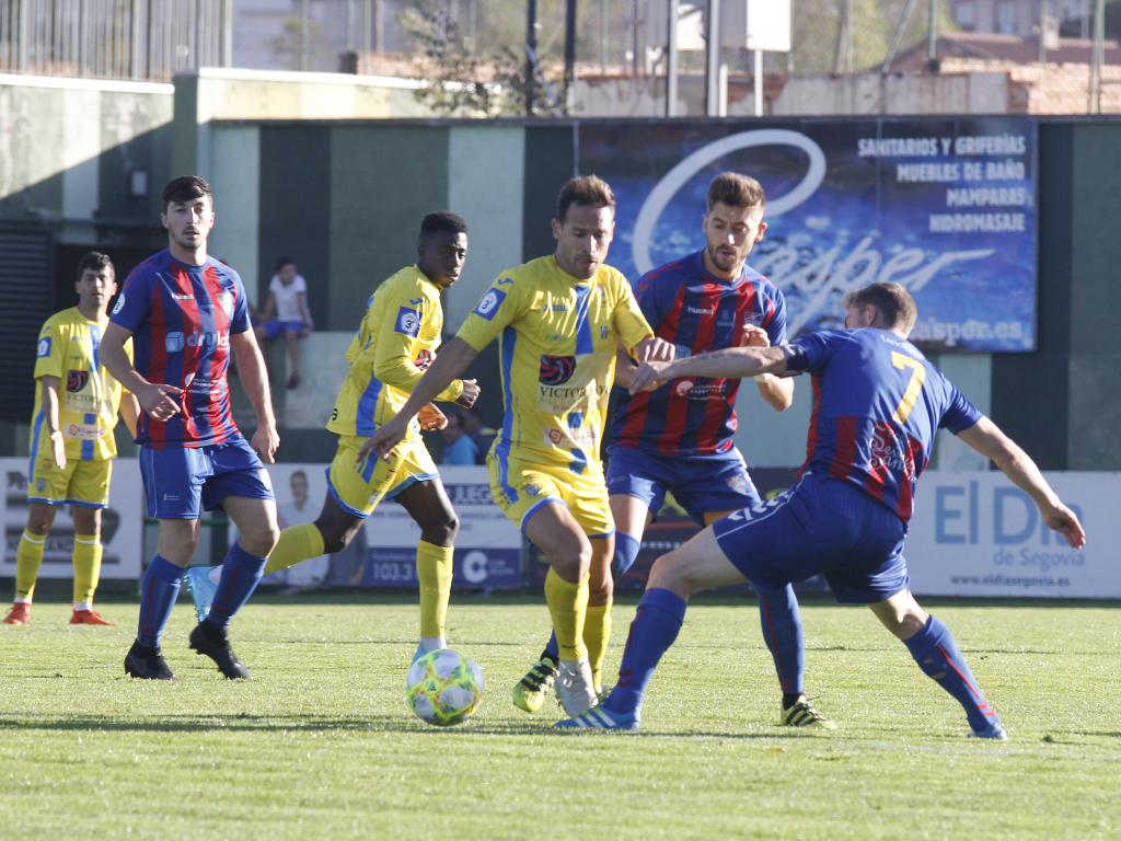 Calleja y Arribas, de la Segoviana, tratan de frenar a Borja Plaza, de la Arandina. / NEREA LLORENTE