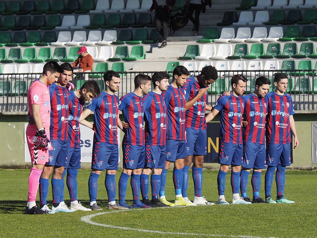 Los jugadores de la Segoviana, unidos mientras se guarda un minuto de silencio en los prolegómenos de un partido en La Albuera./ KAMARERO