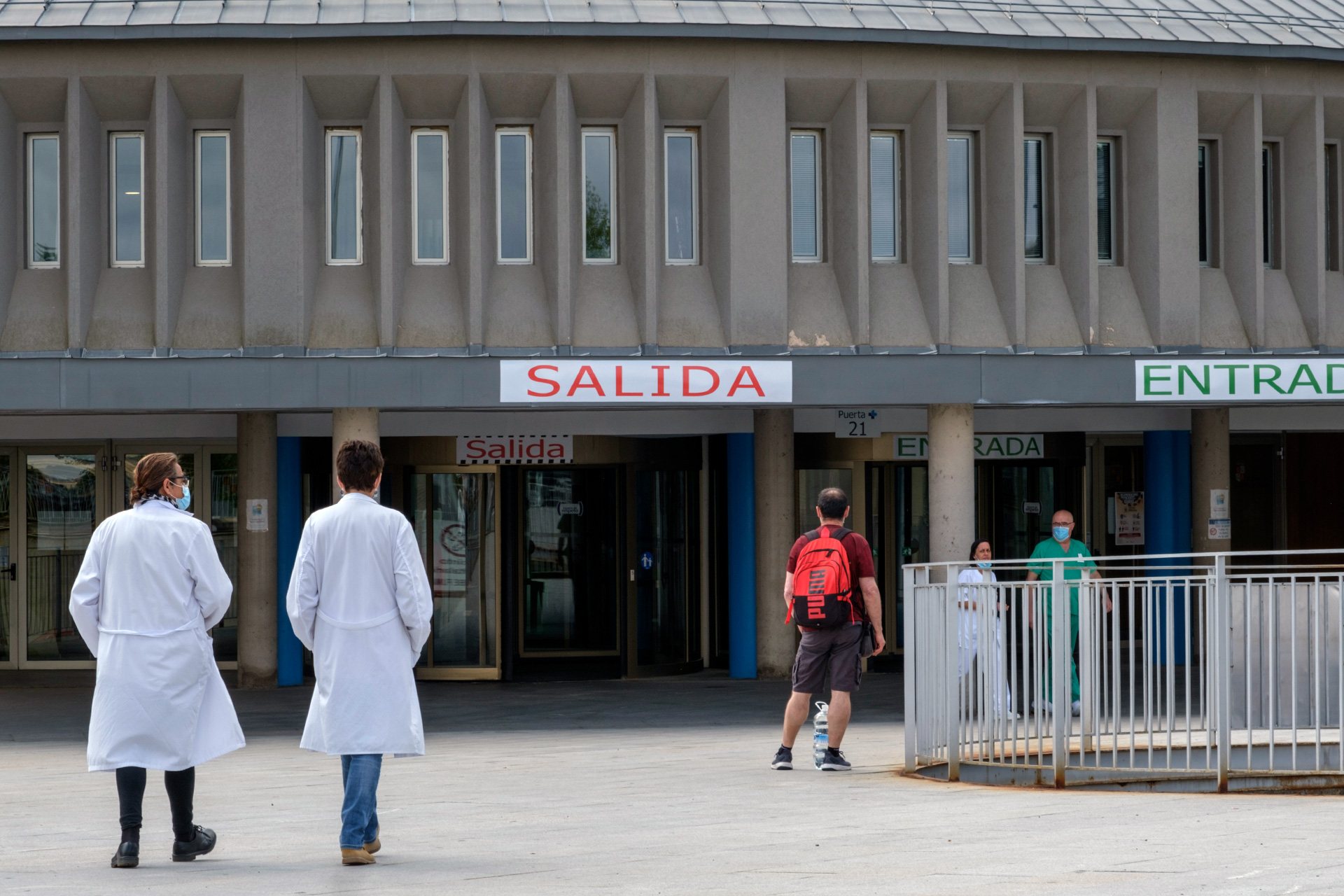 Dos miembros del personal sanitario se dirigen a la entrada del Hospital.