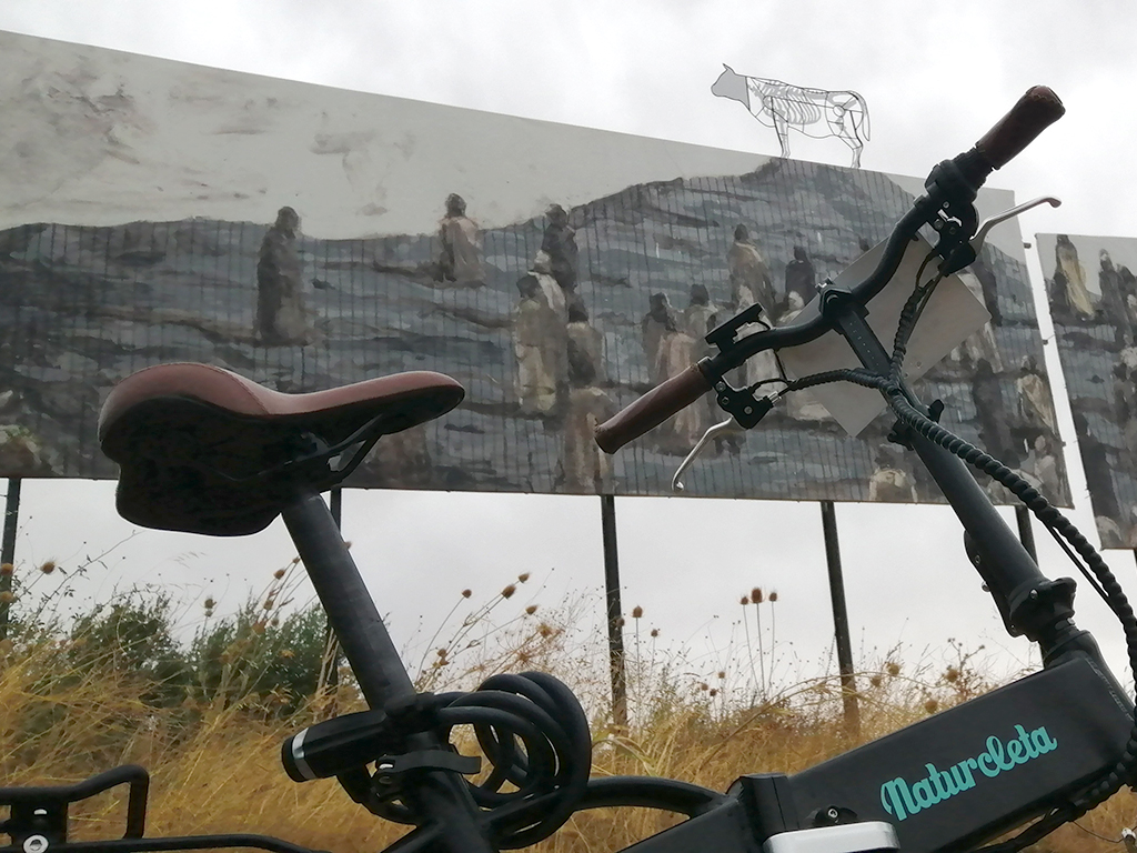 Bicicleta eléctrica frente a una de las vallas de la exposición./ E.A.