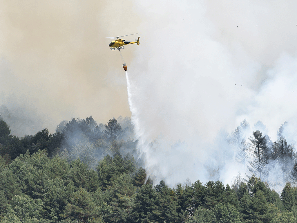Un helicóptero descargando agua para sofocar un incendio. / ROCIO PARDOS
