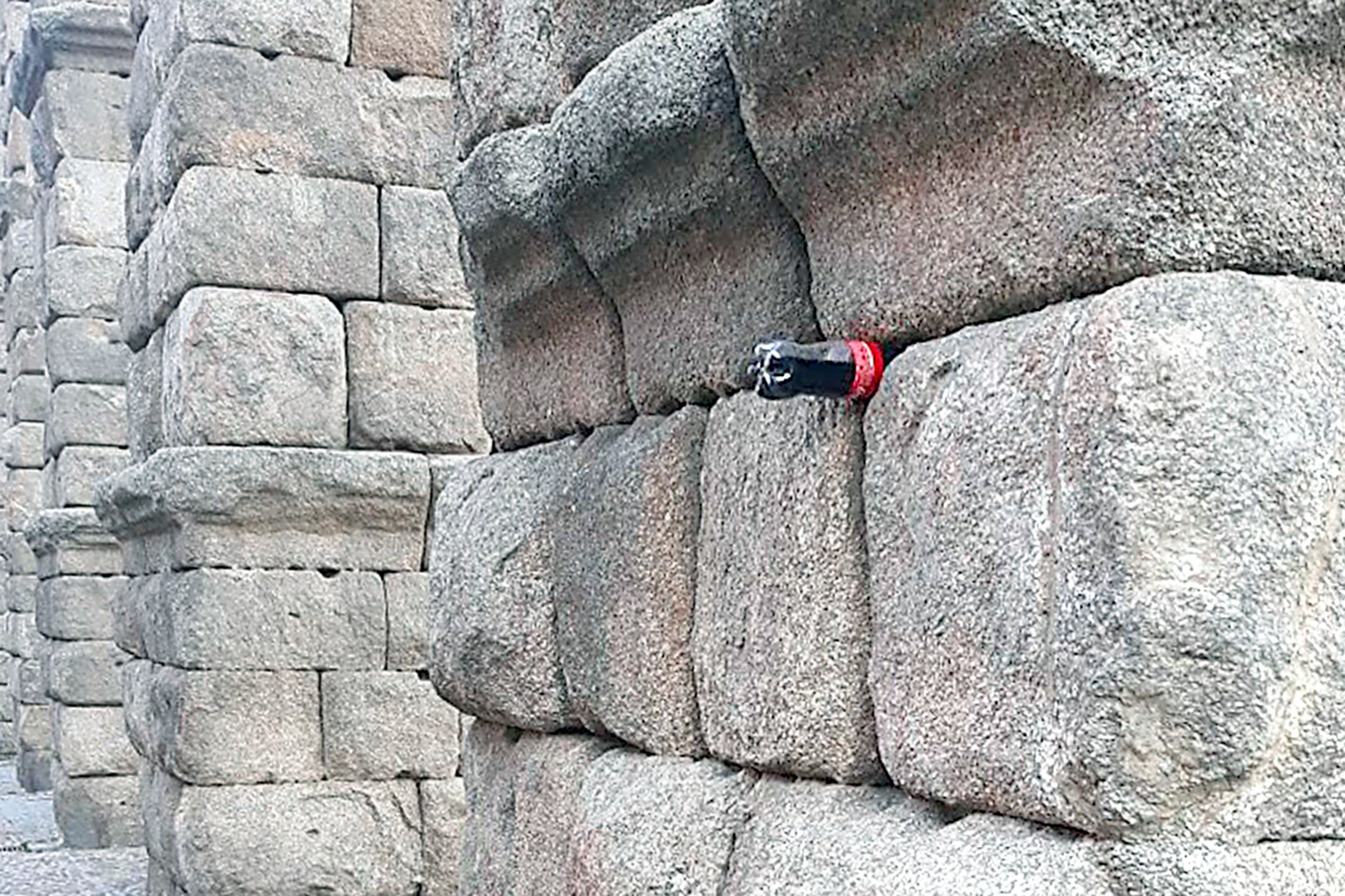 Imagen reciente de una botella de refresco colocada entre los sillares del Acueducto. / E.A.