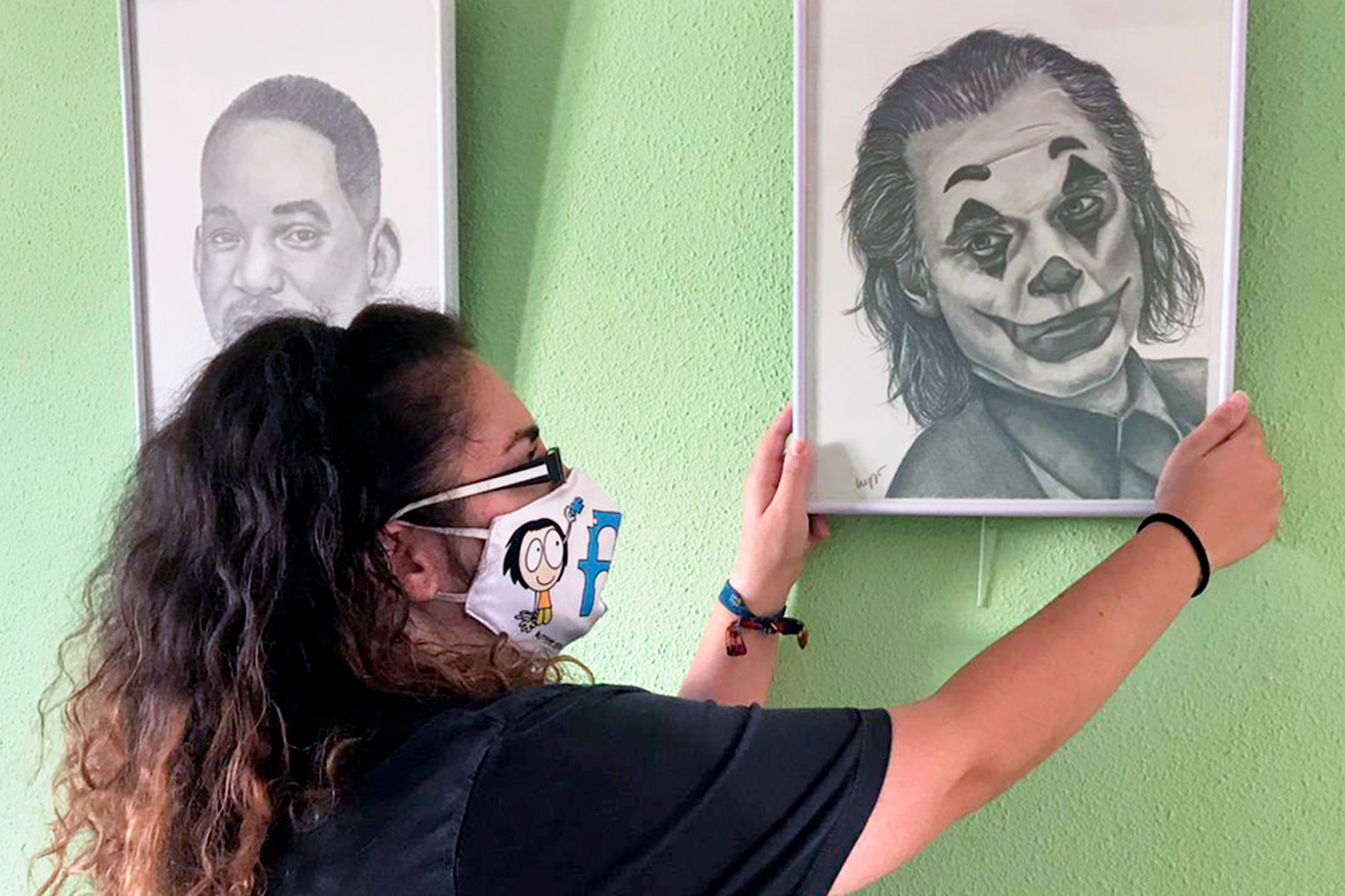 Lucía García, junto al retrato de 'Joker' en la exposición que acoge la Casa Joven. / E.A