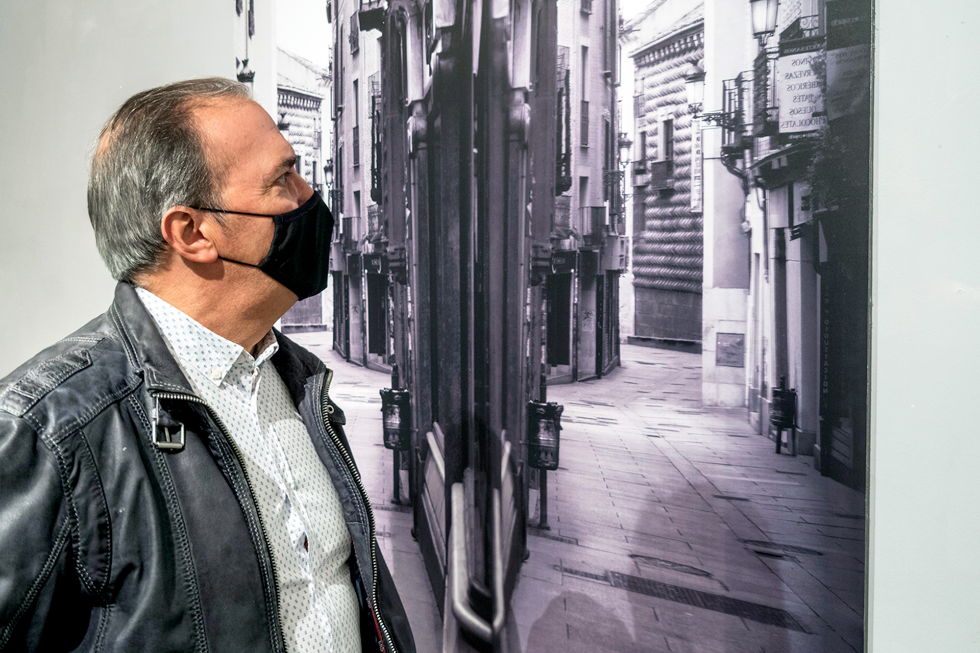 El autor de las fotografías, Juan Luis Misis, junto a una reproducción de la Calle Real durante el confinamiento. / Kamarero