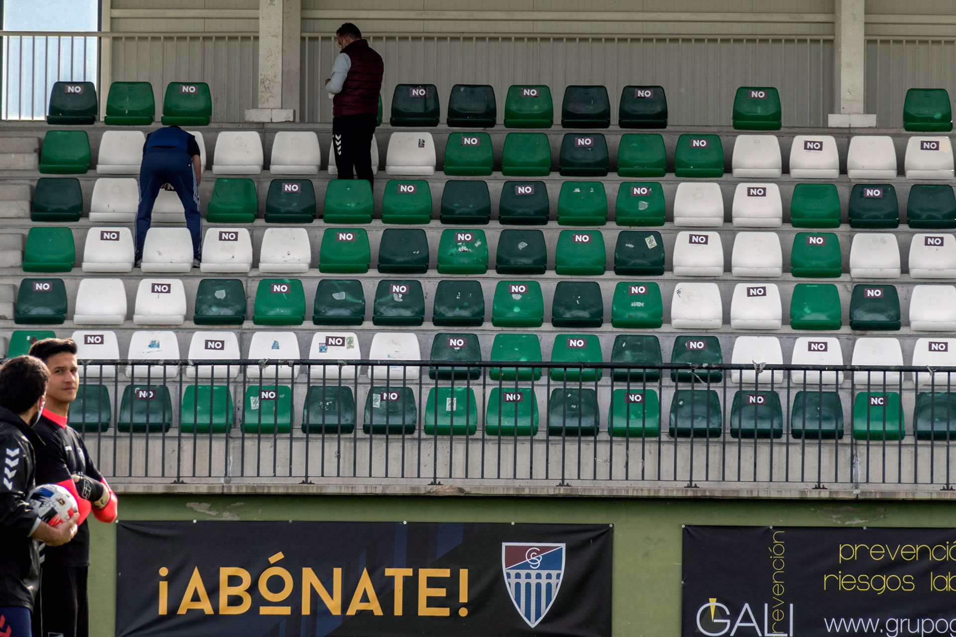 El personal de la Segoviana, poniendo pegatinas en los asientos del campo de La Albuera./ JUAN MARTÍN-G. SEGOVIANA
