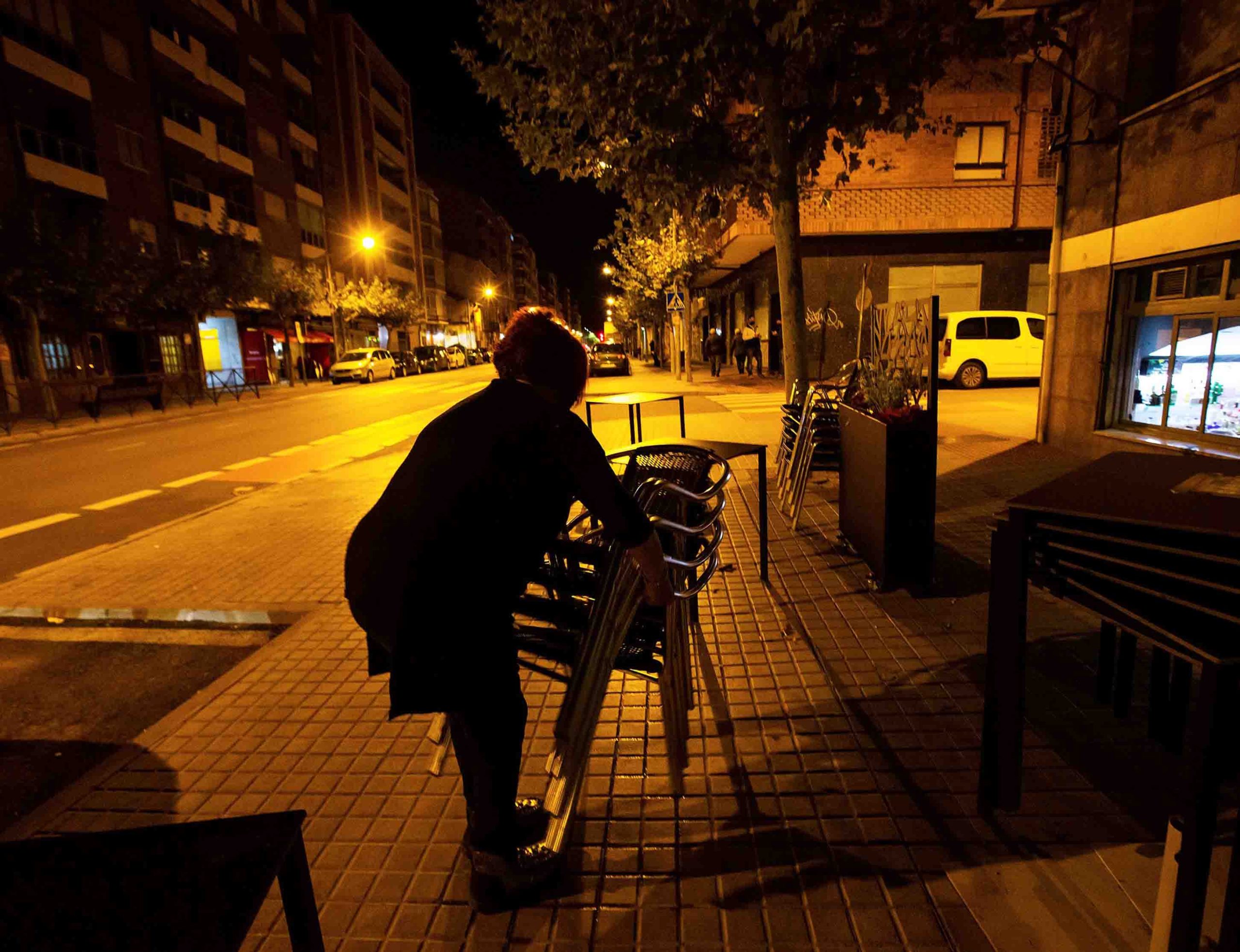 La dueña de un bar recoge la terraza minutos antes de las 22.00 hoy sábado en Aranda de Duero, tras el toque de queda decretado por el Gobierno de Castilla y León. EFE/Paco Santamaría