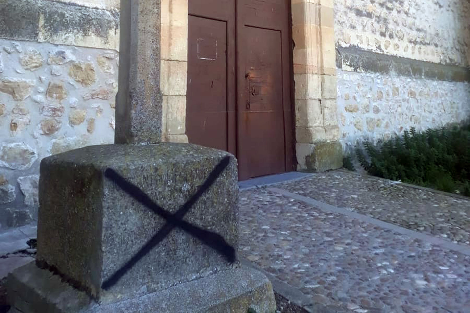 Aspa negra pintada en la cruz  situada en la entrada de la iglesia de Nuestra Señora de la Asunción de Valseca. / A. P.