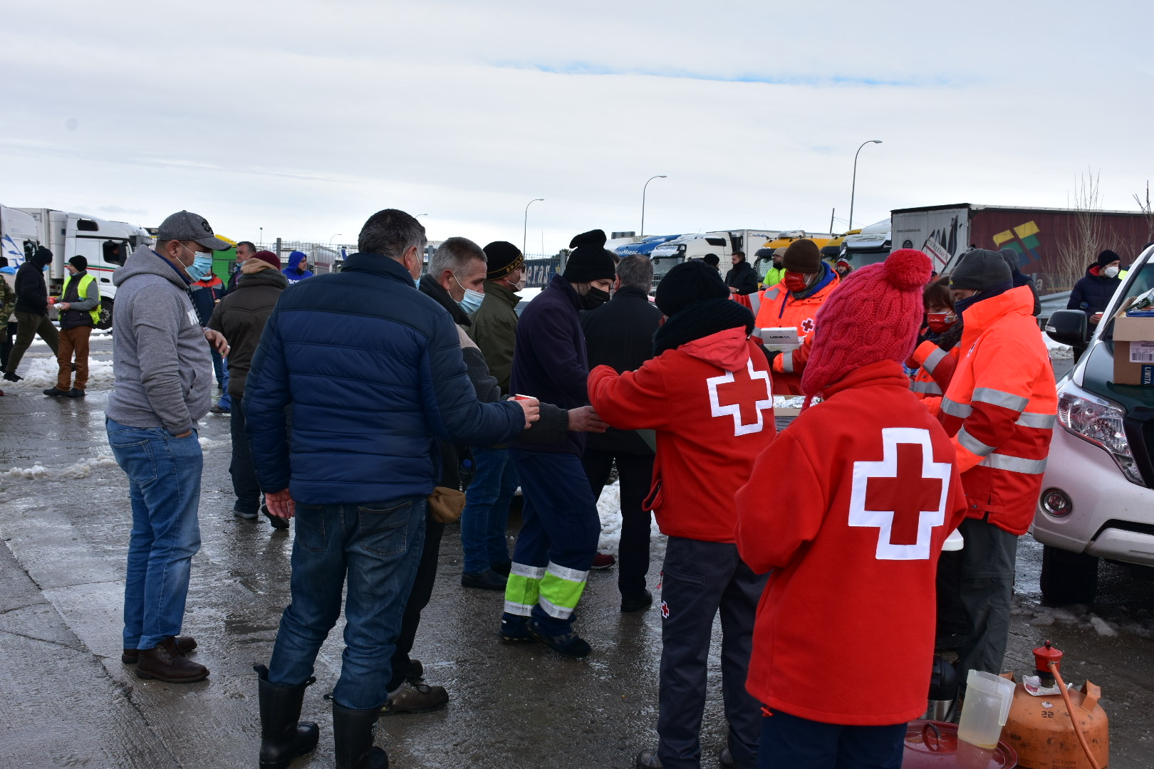 Varios camioneros reciben bebidas calientes en el aparcamiento de emergencia invernal de Boceguillas. / A.M.