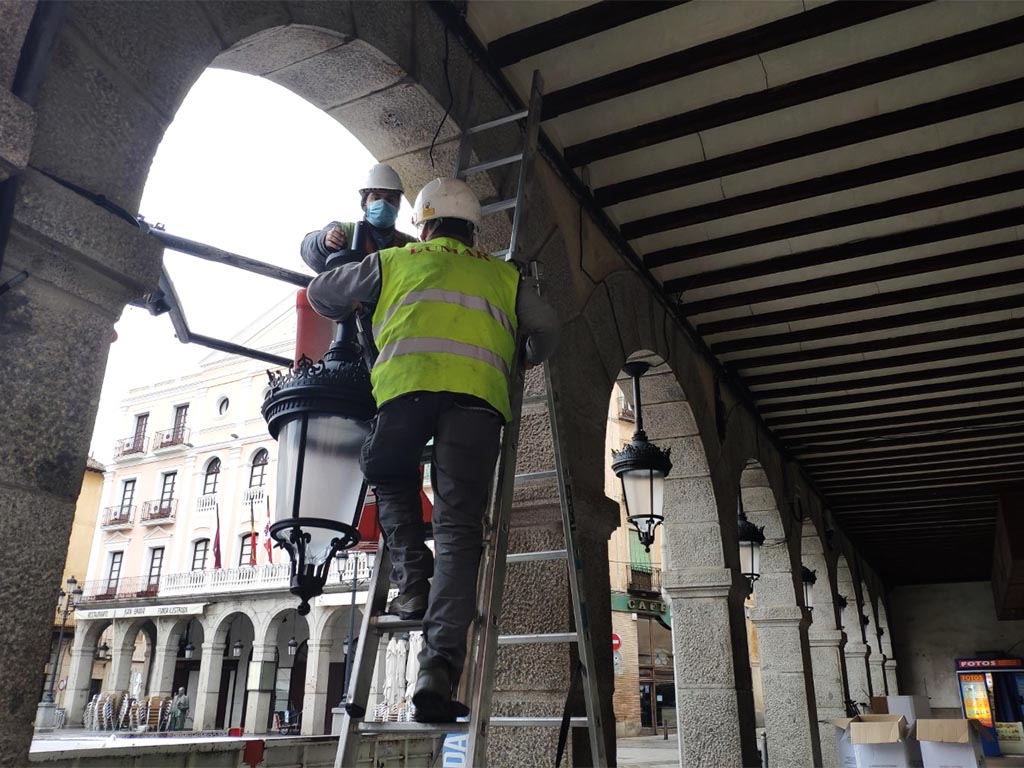 Operarios sustituyen las luminarias de los soportales de la Plaza Mayor de Segovia. / EL ADELANTADO