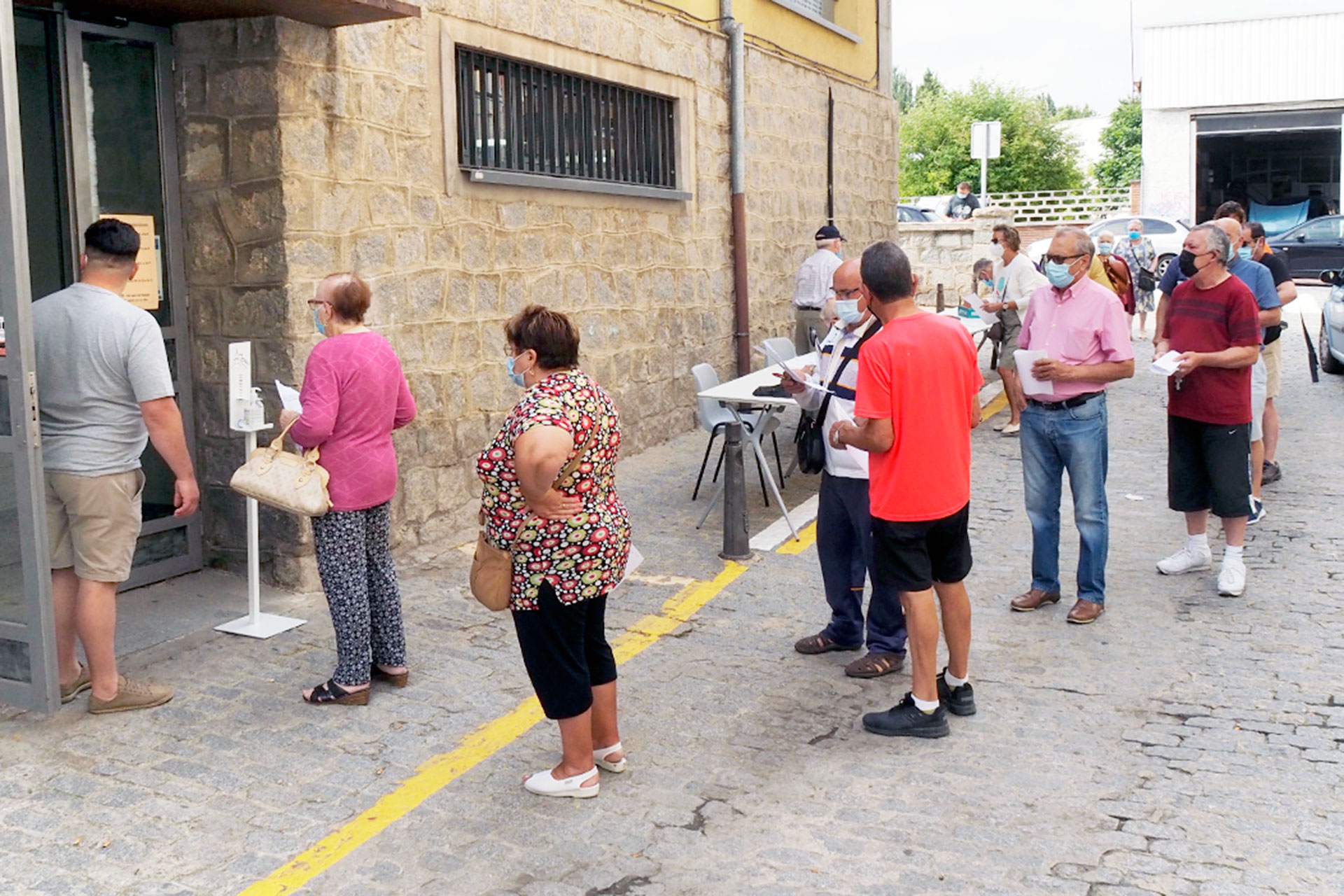 Fila de personas en julio de 2021 en una de las puertas laterales del Centro Civico de San José durante uno de los repartos de mascarillas. / Kamarero