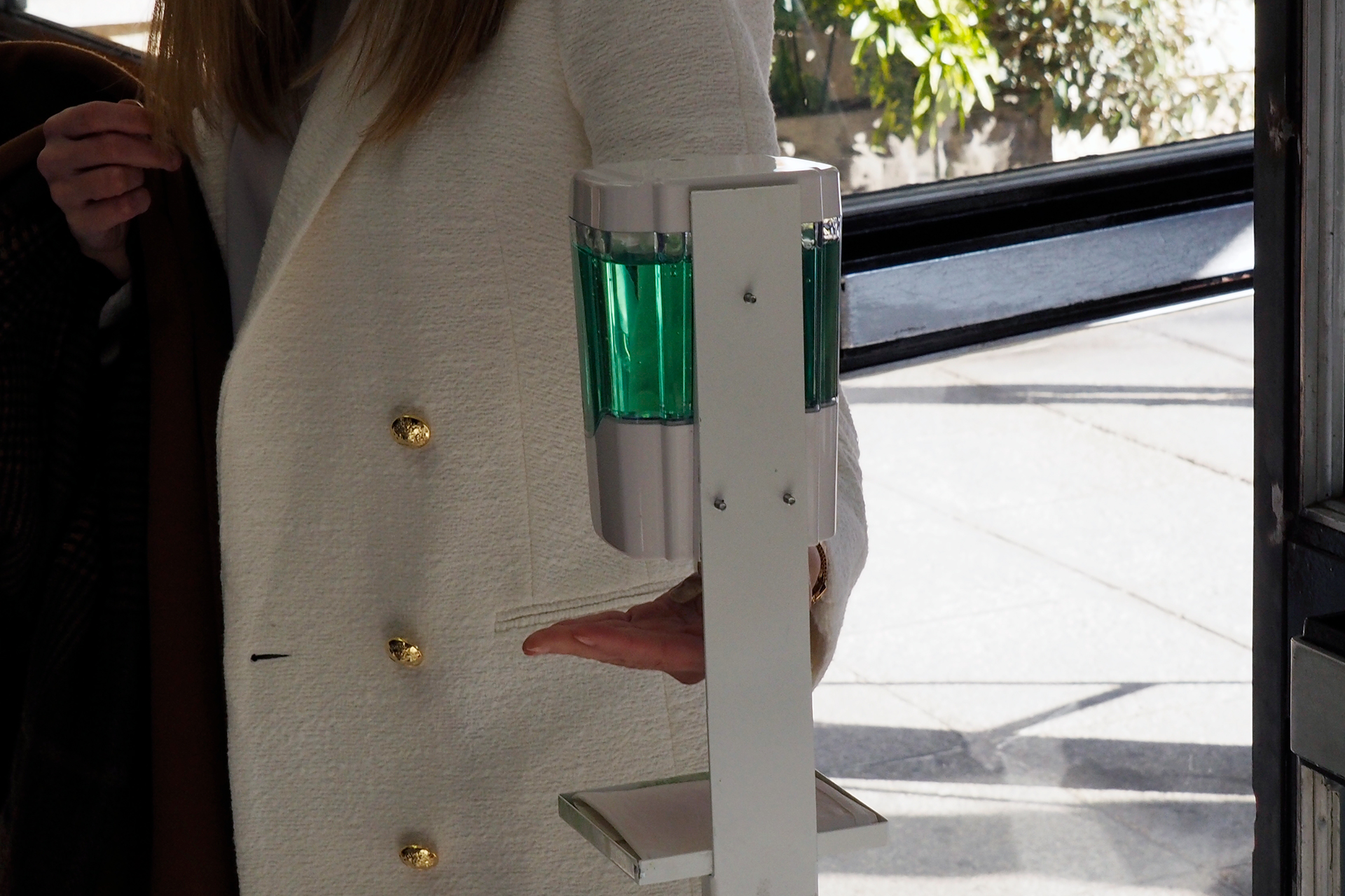 Una mujer se aplica gel hidroalcohólico antes de entrar a un recinto de interior.