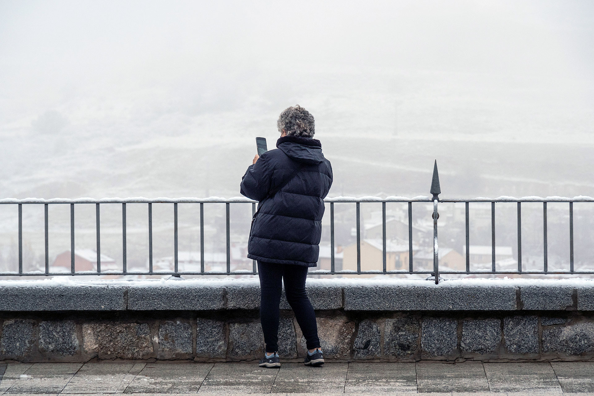 Una persona hace una fotografía a la nieve y niebla desde un punto de la ciudad durante el temporal. / KAMARERO