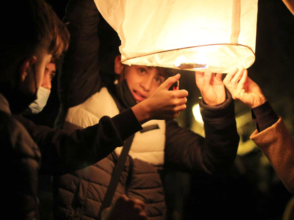 Centenares de farolillos sobrevuelan el cielo de Sebúlcor por una buena causa 1 Un grupo de jóvenes enciende un farolillo. / MARTA CRIADO