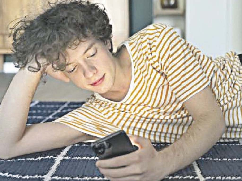 Un adolescente usando el teléfono móvil en su habitación.