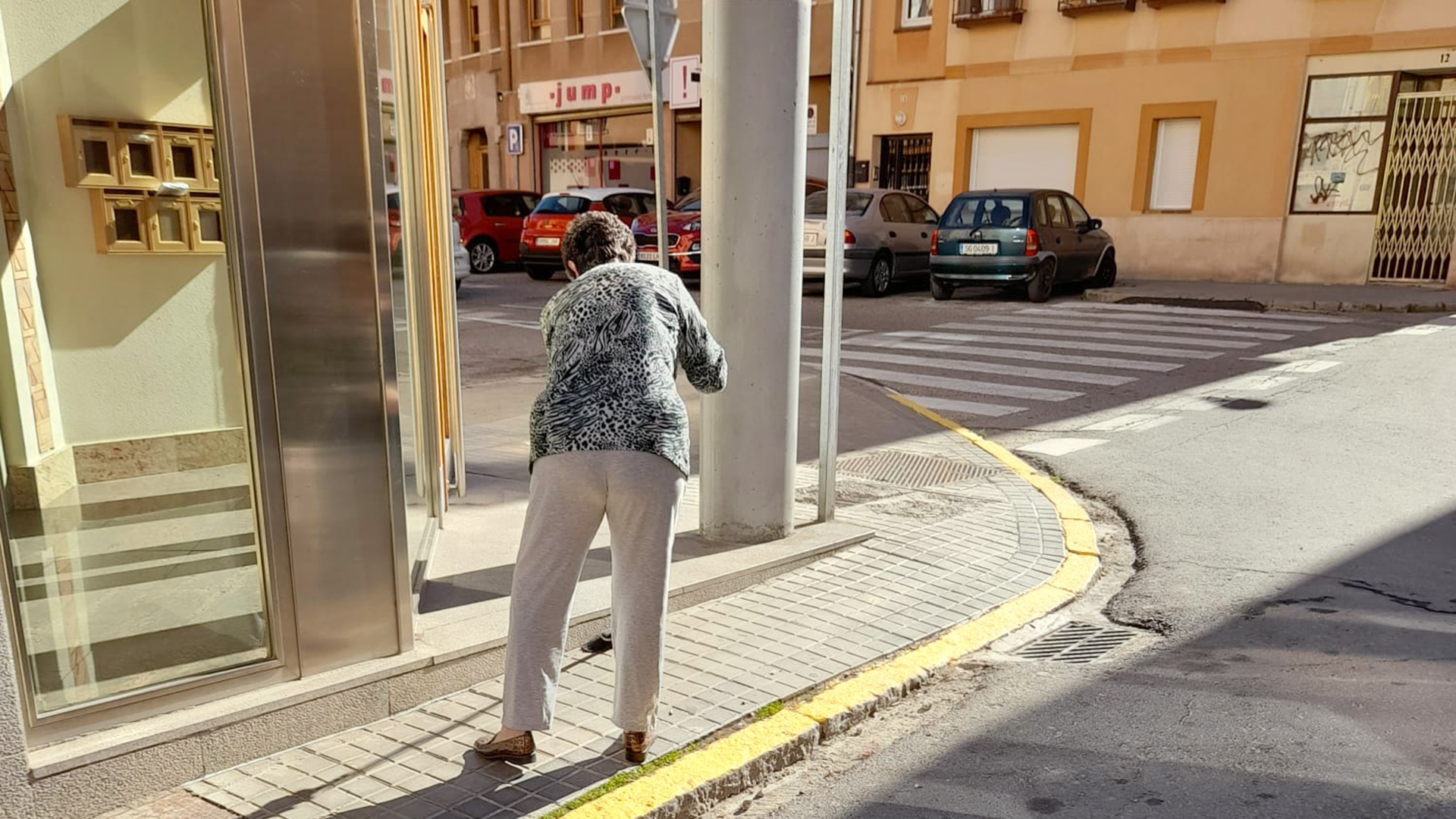 Una ciudadana barre una acera en el barrio de Santa Eulalia. / E. A.