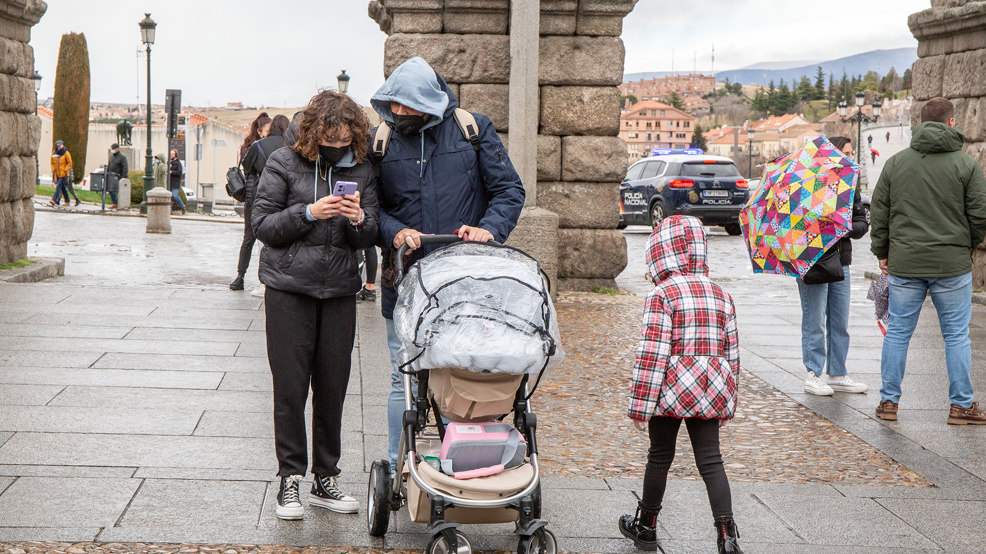 Dos padres pasean junto a su bebé junto al Acueducto. / NEREA LLORENTE