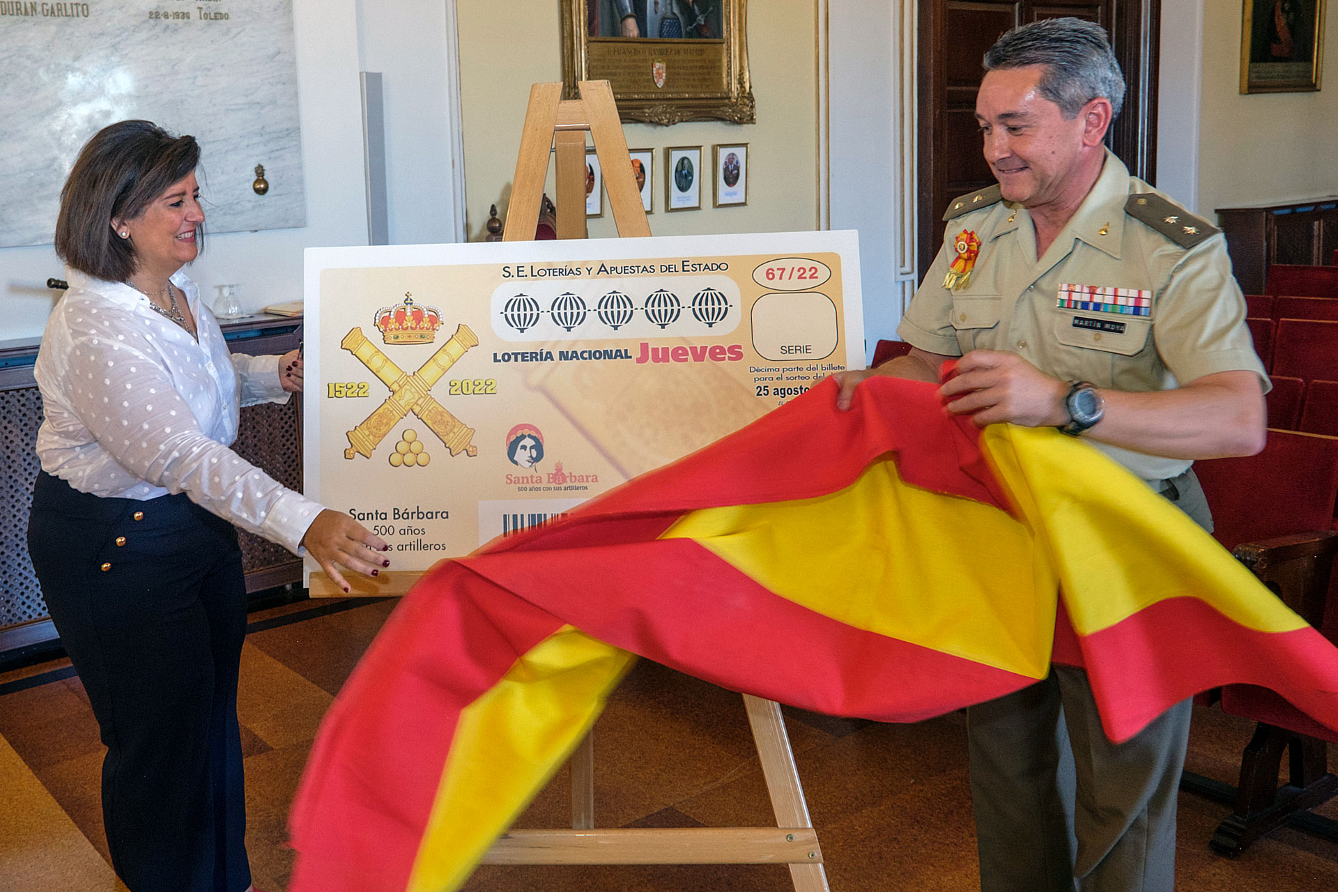 Laura López Caniego y el teniente coronel Martín Moya descubren la imagen del décimo dedicado a la conmemoración artillera. / KAMARERO