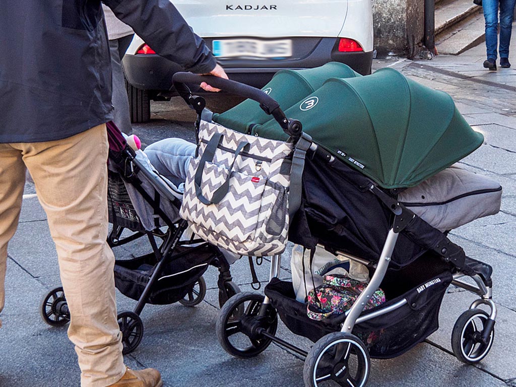 Un padre, con un carrito de dos bebés por el centro de Segovia. / KAMARERO