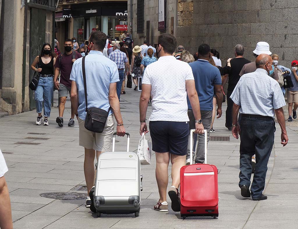 Dos turistas, con sus maletas, subiendo por la Calle Real de Segovia. / KAMARERO