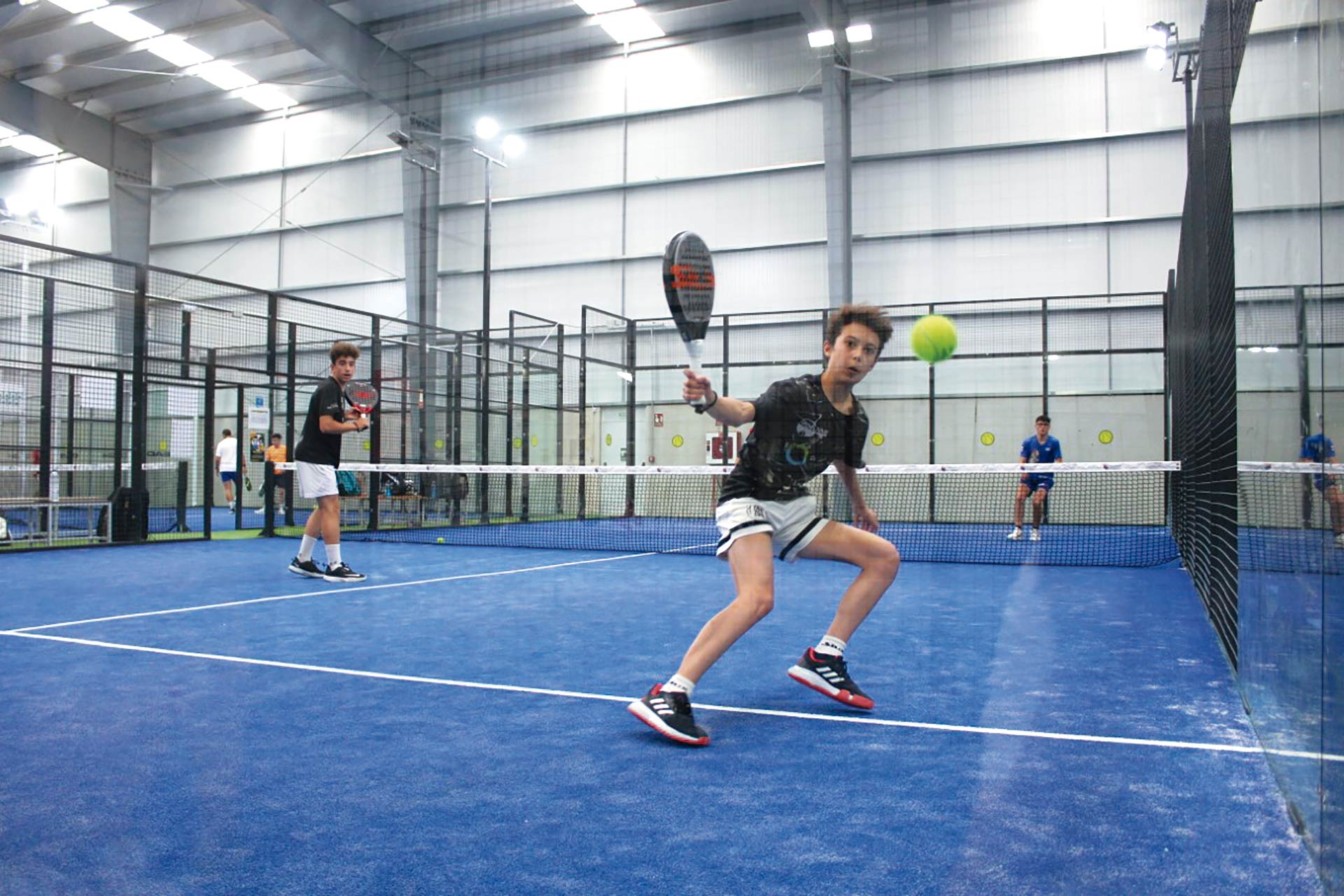 Un joven jugador devuelve la bola tras golpear en la pared de uno de los fondos./ E.A.
